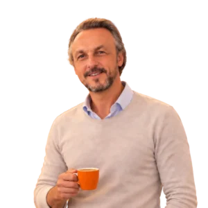 Nicolas Van Caemerbeke, coach professionnel, souriant, une tasse orange de café à la main