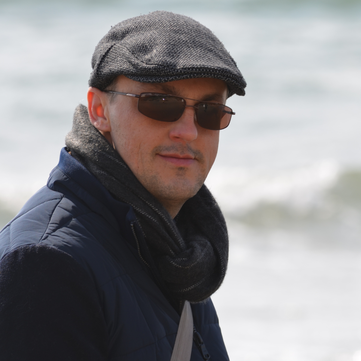Nicolas Van Caemerbeke, casquette et lunettes de soleil, le regard tourné vers l'objectif, au bord de la mer.