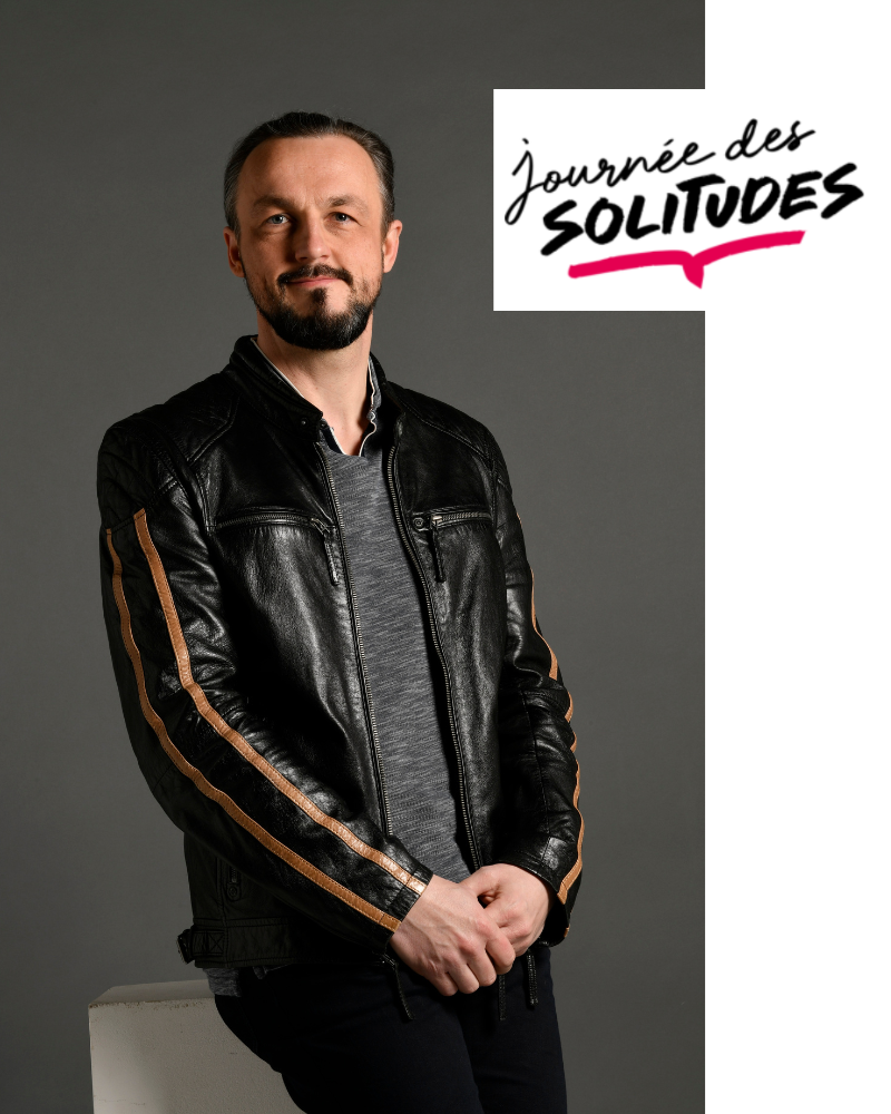 Nicolas Van Caemerbeke, en veste de cuir, assis devant un fond gris, à côté du titre « Journée des solitudes » (1 sur 4).
