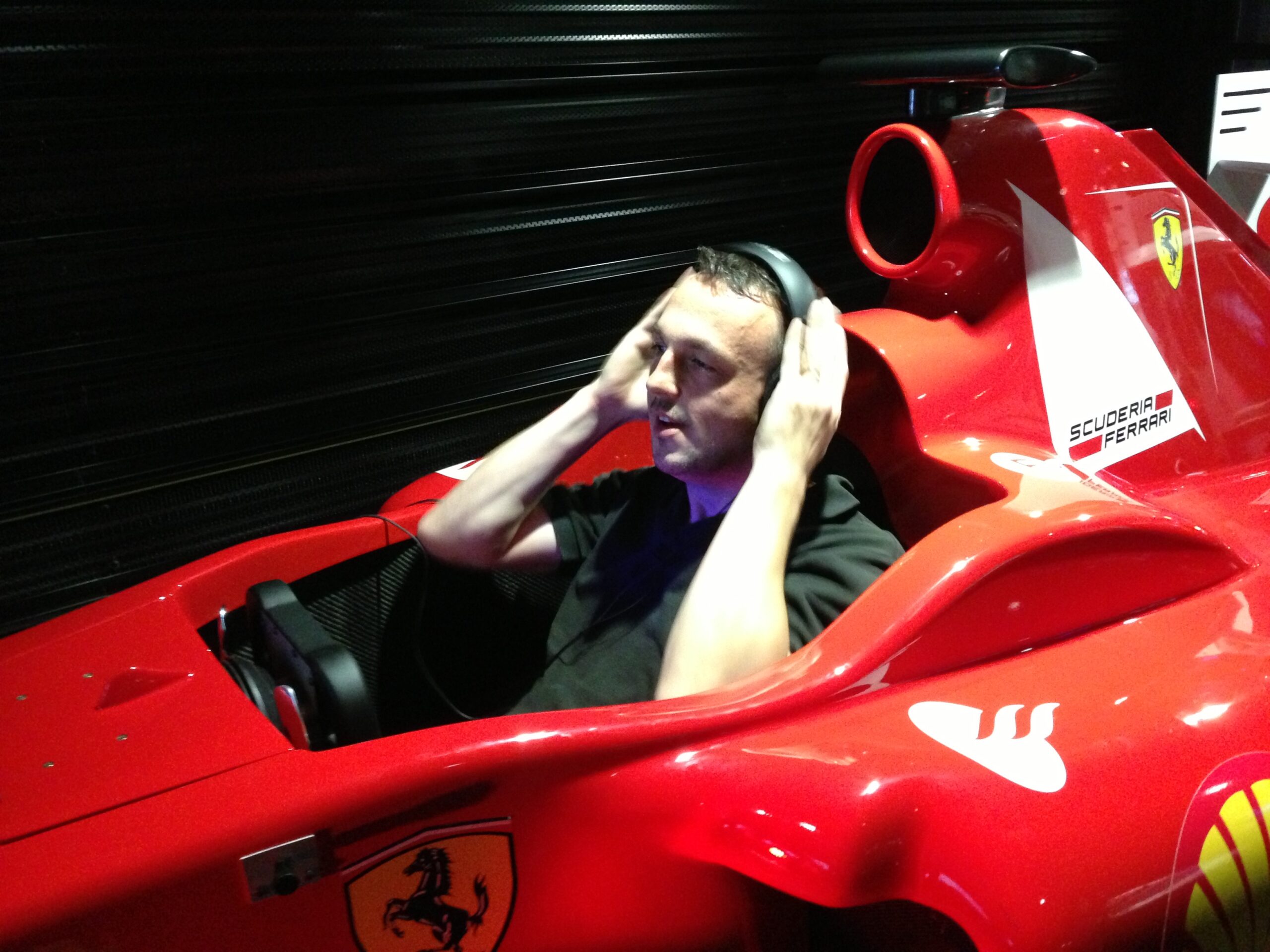 Nicolas Van Caemerbeke, un casque audio sur les oreilles, assis dans le cockpit d'un simulateur de Formule 1 rouge.